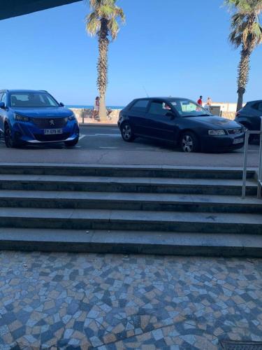 twee auto's geparkeerd naast een trap bij het strand bij Studio au Front de la Mer in Canet-en-Roussillon