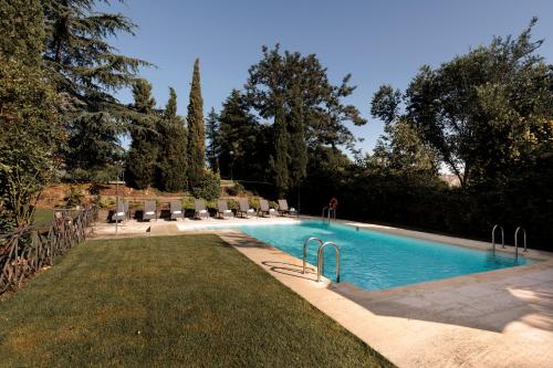 uma piscina num quintal com árvores e relva em Hotel PAX Torrelodones em Torrelodones