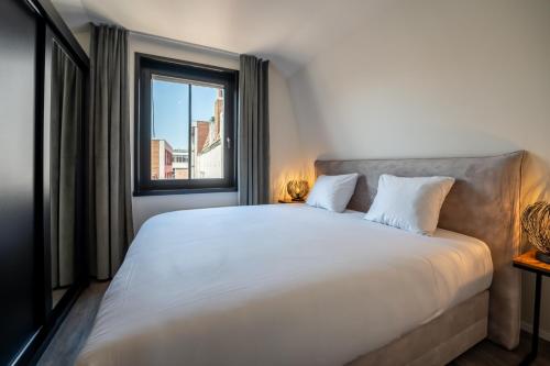 a bedroom with a large white bed with a window at Hotel Residentie Vlissingen in Vlissingen