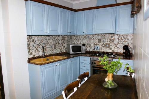 a kitchen with blue cabinets and a wooden table at Vacaciones tierra y mar Casa en el centro con patio y terraza in El Campello