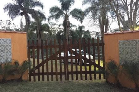 une porte en bois avec des palmiers derrière une clôture dans l'établissement Recanto Vista Mantiqueira, à Guararema