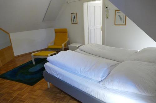 ein Schlafzimmer mit einem weißen Bett und einem Stuhl in der Unterkunft Traumhafte Maisonnette mit Kamin in Wien