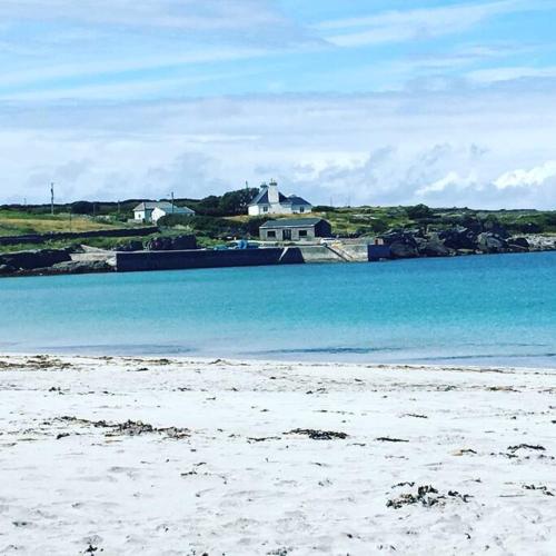 a beach with blue water and houses in the background at Irish Isle Oasis: Spacious 5-Bedroom Retreat in Bungowla