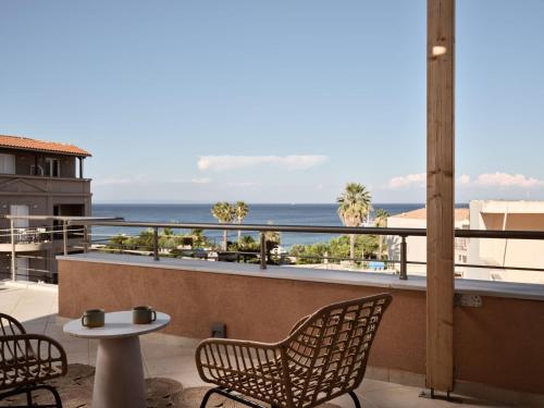 a balcony with chairs and a table and the ocean at Laura Suites in Zakynthos