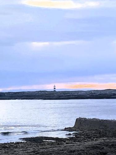 a lighthouse on the shore of a body of water at Irish Isle Oasis: Spacious 5-Bedroom Retreat in Bungowla