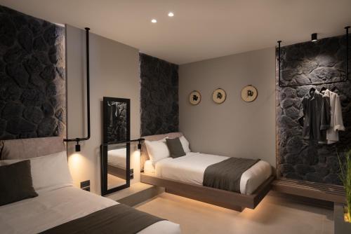 a bedroom with two beds and a wall witharmor at Apikia Santorini in Pirgos