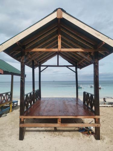 a wooden pavilion on a beach with the ocean at Villa panrangluhu in Bira