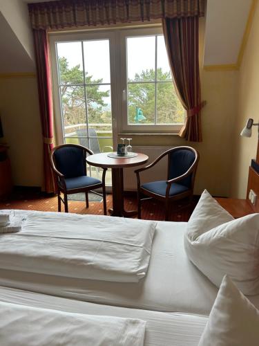 a hotel room with a bed and a table and chairs at Hotel Ostseeblick - direkt hinter den Dünen in Ostseebad Karlshagen