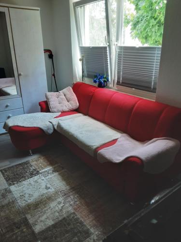 um sofá vermelho sentado num quarto com uma janela em Zimmer Anna em Parchim