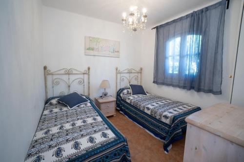 um quarto com 2 camas e uma janela com um lustre em Mandarinos 16 Urb SJ de Capistrano em Nerja