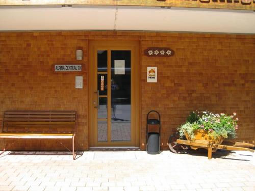 a building with a door and a bench and flowers at Alpina Central in Brand