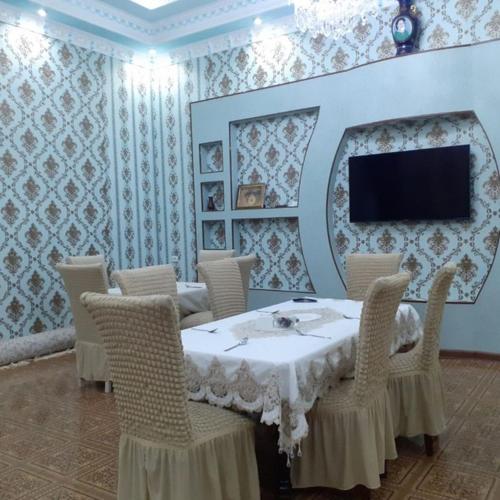 a dining room with a table and chairs and a tv at UYUT INN Hotel in Samarkand