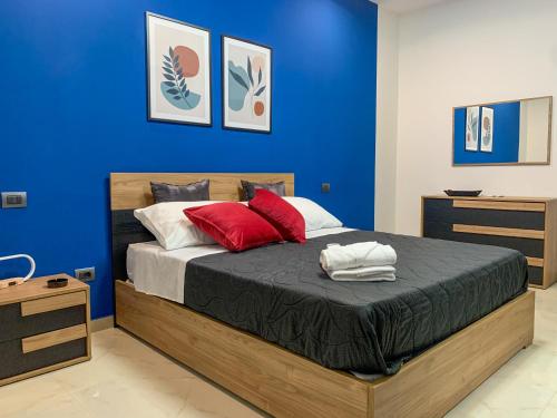 Dormitorio azul con cama con almohadas rojas en Griseo - Sicily Holiday House, en Misterbianco