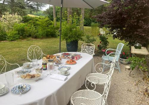 - une table avec de la nourriture, des chaises et un parasol dans l'établissement La Rochelière, à Bresse-sur-Grosne