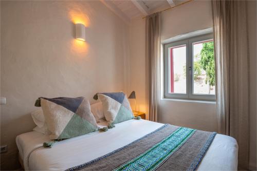 1 dormitorio con 1 cama y ventana en Nômade Melides Eco Lodge, en Melides