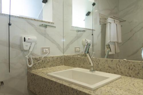 a bathroom with a sink and a phone on a counter at Principe do Mutá Hotel Design in Santa Cruz Cabrália