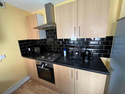 a kitchen with a stove and a black tile wall at Newcastle, Powburn, fully equipped kitchen 4 bedrooms, 3 king & 2 single beds in Newcastle upon Tyne
