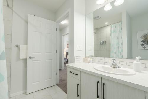 a white bathroom with a sink and a mirror at 3bedroom Stylish Getaway by the Park with 2-Car Garage in Calgary