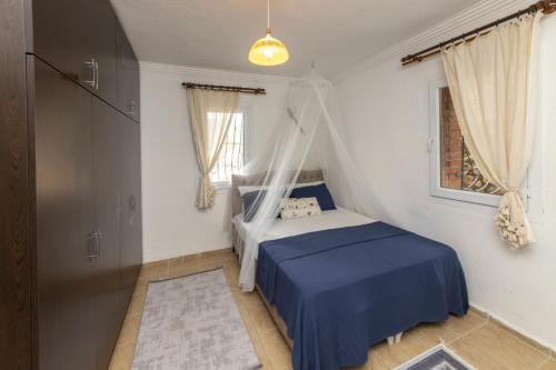 a bedroom with a bed with blue sheets and a window at Refreshing Villa near Milas-Bodrum Airport in Gulluk