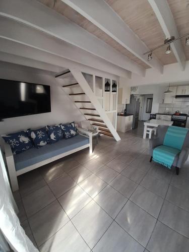 a living room with a couch and a staircase at @ the reef Holiday Home in St. Helena Bay