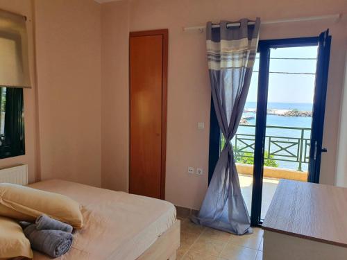a bedroom with a bed and a door to a balcony at Island apartment N.Skioni in Nea Skioni