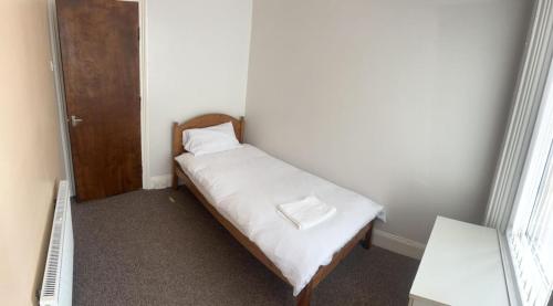a small bedroom with a bed with white sheets at Newcastle, Powburn, fully equipped kitchen 4 bedrooms, 3 king & 2 single beds in Newcastle upon Tyne