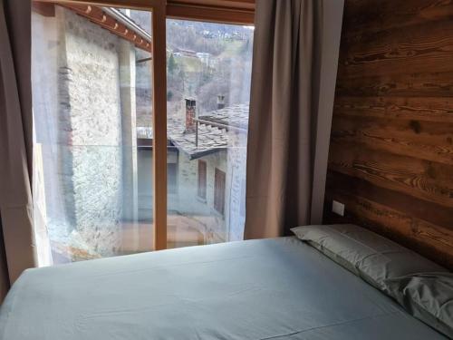 a bed in a room with a large window at ChaletMagnan in Lanzada