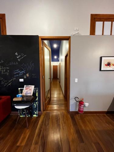 a hallway with a chalkboard on the wall and a room with a table at Hostel Matilda in Curitiba