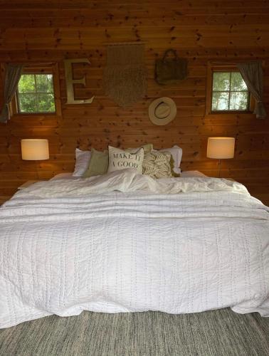 Koselig hytte langs elven في شين: سرير أبيض كبير في غرفة خشبية مع مصباحين