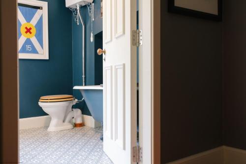 La salle de bains est pourvue de toilettes et d'un mur bleu. dans l'établissement Exclusive use - The Coach House, à Banchory