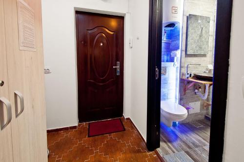 La salle de bains est pourvue d'une porte marron et de toilettes. dans l'établissement Boutique Apartments, à Galaţi