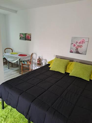 - une chambre avec un grand lit noir et des oreillers jaunes dans l'établissement Le Jardin Serein, à Salindres