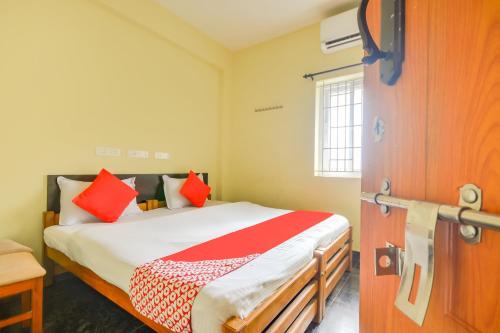 um quarto com uma cama com almofadas vermelhas em OYO St Residency em Mudukarai