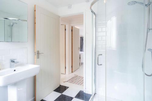 uma casa de banho branca com um lavatório e um chuveiro em Norton Cottage - 3 Bedroom Cottage - Tenby em Tenby