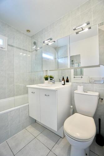 une salle de bain blanche avec des toilettes et un lavabo dans l'établissement Duplex des 4 chemins, à Larmor-Plage
