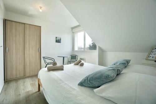 une chambre avec un grand lit blanc avec des oreillers bleus dans l'établissement Duplex des 4 chemins, à Larmor-Plage