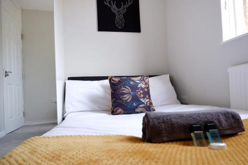 Bett mit Kissen und zwei Fernbedienung in der Unterkunft COMFORTABLE 4-Bed HOME WITH 3 BATHROOMS AND FREE PARKING! in Cambridge