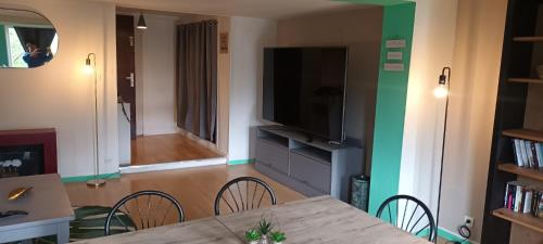 une salle à manger avec une table avec des chaises et une télévision dans l'établissement L'Yser - Appartement proche de la gare - Rouen, à Rouen