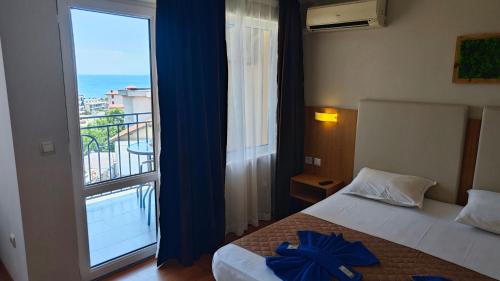 a hotel room with a bed and a large window at Family Hotel Milev in Sveti Vlas
