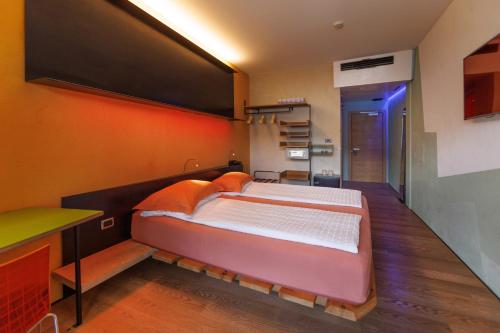 a bedroom with a large bed with an orange wall at Ambienthotel PrimaLuna 3S in Malcesine