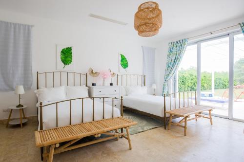 a white bedroom with a bed and two chairs at Tranquil Lakefront 5-Bedroom Villa with Cook, Maid, Golf Cart, and Beach Access in Punta Cana in Punta Cana