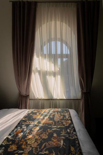 a bedroom with a bed with a curtain and a window at Puris Moedani Boutique Hotel in Tbilisi City