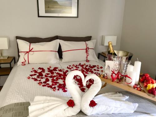 ein Bett mit zwei herzförmigen Handtüchern und Rosen in der Unterkunft Kamburinn Cottage in Hveragerði