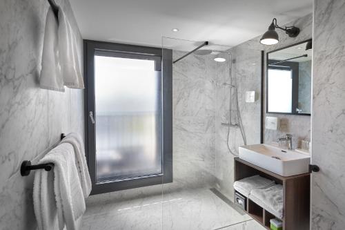 a bathroom with a sink and a shower with a window at Nova Apartments Amsterdam in Amsterdam