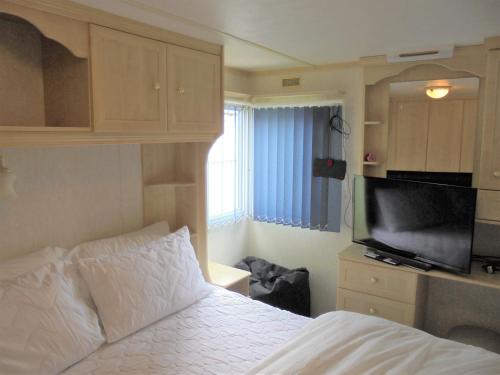 a bedroom with a bed and a flat screen tv at Seaview: The Crown:- 6 Berth, Central heated, Enclosed Veranda in Ingoldmells