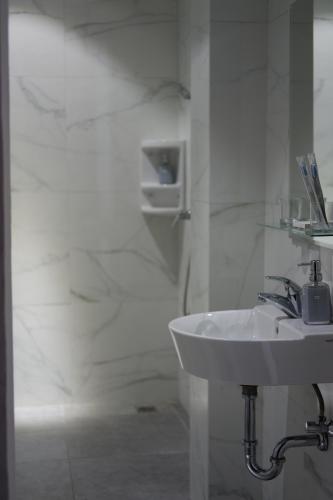 a white bathroom with a sink and a shower at Lun Hotel Manado in Manado