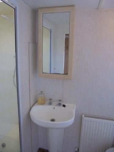 a white bathroom with a sink and a mirror at Seaview: The Crown:- 6 Berth, Central heated, Enclosed Veranda in Ingoldmells