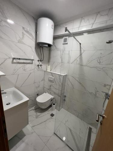 a white bathroom with a toilet and a sink at Apartments MAMPAS in Neum