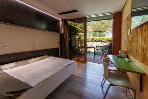 a bedroom with a bed and a desk and a table at Ambienthotel PrimaLuna 3S in Malcesine