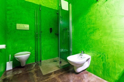 a green bathroom with a toilet and a sink at Ambienthotel PrimaLuna 3S in Malcesine
